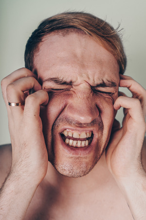 emotional portrait of a crazy guy in closeup. concept: the nervous breakdown, mental disease, headaches and migraineの写真素材