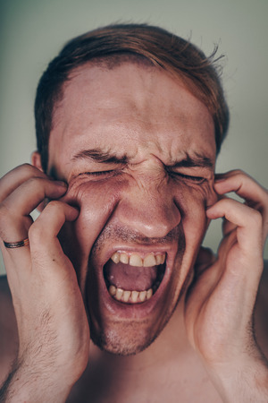 emotional portrait of a crazy guy in closeup. concept: the nervous breakdown, mental disease, headaches and migraineの写真素材