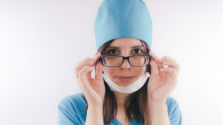 Portrait of a friendly smiling doctor woman or nurse in blue medical uniform, isolated on white background with copy space. Healthcare and medicine conceptの写真素材