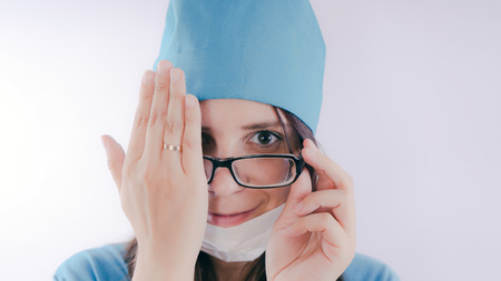 Portrait of a friendly smiling doctor. Hand closed one eye, the concept of "vision check", isolated on white background with copy space. Healthcare and medicineの写真素材