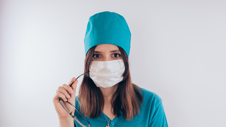 Portrait of a friendly smiling doctor woman or nurse in blue medical uniform, isolated on white background with copy space. Healthcare and medicine conceptの写真素材
