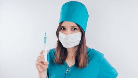 Portrait of a friendly smiling doctor woman or nurse in white medical uniform with a syringe, isolated on white background with copy space. Healthcare and medicine conceptの写真素材