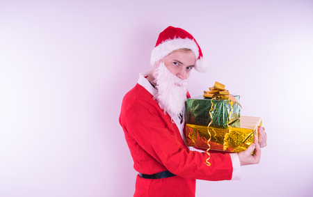 Portrait of thin Santa Claus with Christmas gifts. Happy Santa Claus holding gift boxes isolated on white background. Santa Claus carries gifts to children.の写真素材