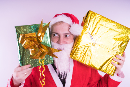 Portrait of thin Santa Claus with Christmas gifts. Happy Santa Claus holding gift boxes isolated on white background. Santa Claus carries gifts to children.の写真素材