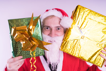 Portrait of thin Santa Claus with Christmas gifts. Happy Santa Claus holding gift boxes isolated on white background. Santa Claus carries gifts to children.の写真素材