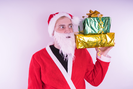 Portrait of thin Santa Claus with Christmas gifts. Happy Santa Claus holding gift boxes isolated on white background. Santa Claus carries gifts to children.の写真素材