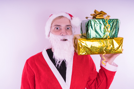 Portrait of thin Santa Claus with Christmas gifts. Happy Santa Claus holding gift boxes isolated on white background. Santa Claus carries gifts to children.の写真素材