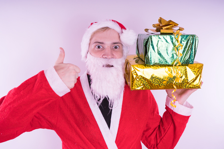 Portrait of thin Santa Claus with Christmas gifts. Happy Santa Claus holding gift boxes isolated on white background. Santa Claus carries gifts to children.の写真素材