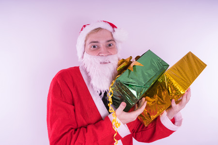 Portrait of thin Santa Claus with Christmas gifts. Happy Santa Claus holding gift boxes isolated on white background. Santa Claus carries gifts to children.の写真素材