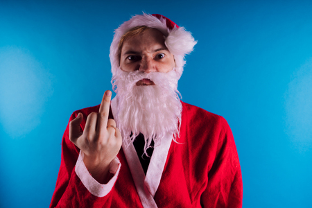 Emotional Santa Claus on a blue background. The concept of bad Santa Claus. Happy New Year and merry Christmas!の写真素材
