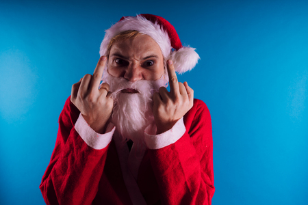 Emotional Santa Claus on a blue background. The concept of bad Santa Claus. Happy New Year and merry Christmas!の写真素材