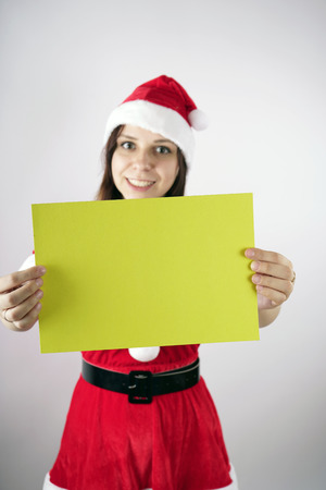 Girl in a suit "Santa Claus" with a sign on a white background. The concept of discounts and sales for Christmas. Discount on holiday. Empty space for textの写真素材