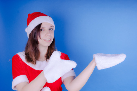 Portrait of a young girl dressed as Santa Claus on a blue background. Happy New Year and merry Christmas!の写真素材
