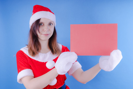 Portrait of a young girl dressed as Santa Claus on a blue background. Happy New Year and merry Christmas!の写真素材