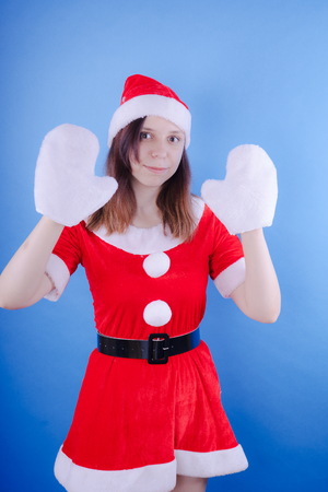 Portrait of a young girl dressed as Santa Claus on a blue background. Happy New Year and merry Christmas!の写真素材