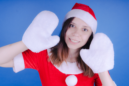 Portrait of a young girl dressed as Santa Claus on a blue background. Happy New Year and merry Christmas!の写真素材
