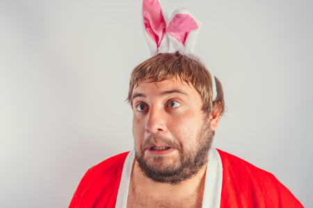 Emotional fat man with a beard. in a red coat with Bunny ears. isolated on whiteの写真素材