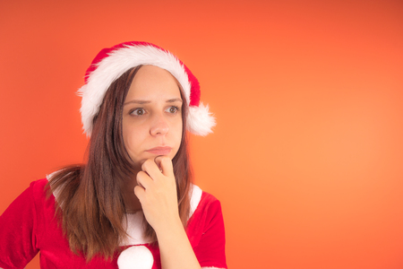 Portrait of a young girl dressed as Santa Claus on orange background. Happy New Year and merry Christmas!の写真素材