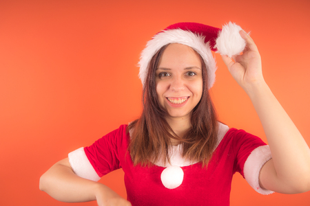 Portrait of a young girl dressed as Santa Claus on orange background. Happy New Year and merry Christmas!の写真素材