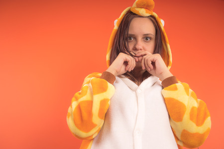 pajamas in the form of a giraffe. emotional portrait of a girl on an orange background. crazy and funny woman in a suit. animator for childrens partiesの写真素材