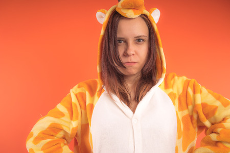 pajamas in the form of a giraffe. emotional portrait of a girl on an orange background. crazy and funny woman in a suit. animator for childrens partiesの写真素材