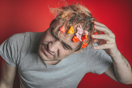 Gum in his head. Portrait of a man with chewing gum in his head. Man with hair covered in food. Hen red hairの写真素材