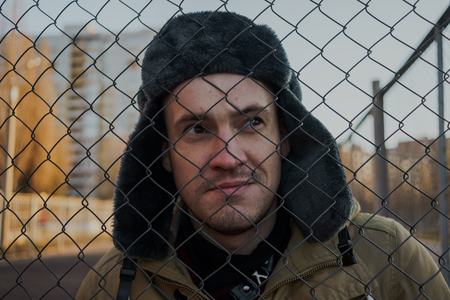 Happy handsome young man in cap with earflaps. The young man in the fur hat. standing on a cloudy day. emotional portrait of a student. street styleの写真素材