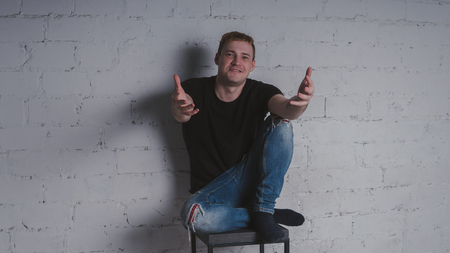 A handsome man in black t-shirt, against a gray brick wall. Brutal guy with a tattooの写真素材