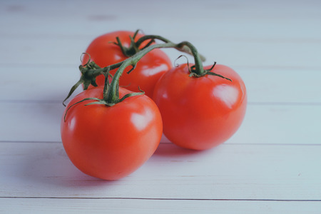 Red, juicy tomatoes on wooden background, concept: fresh vegetables, healthy food.の写真素材