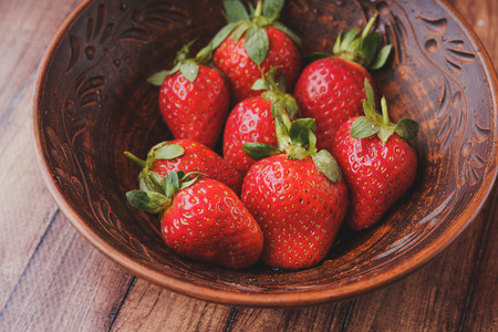 Fresh strawberries in a clay plate. Fresh berries on the table. Red strawberries in a brown bowl. Fruit close-upの写真素材