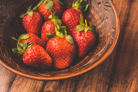 Fresh strawberries in a clay plate. Fresh berries on the table. Red strawberries in a brown bowl. Fruit close-upの写真素材