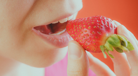 Girl eating fresh strawberries, close-up. Red strawberries in a woman's hand. Concept: Fruits and slim figureの写真素材