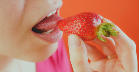 Girl eating fresh strawberries, close-up. Red strawberries in a woman's hand. Concept: Fruits and slim figureの写真素材