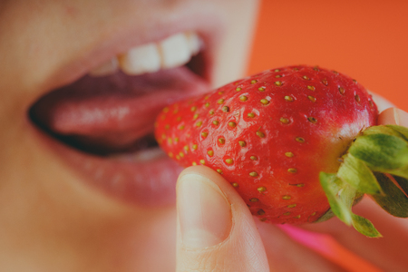 Girl eating fresh strawberries, close-up. Red strawberries in a woman's hand. Concept: Fruits and slim figureの写真素材