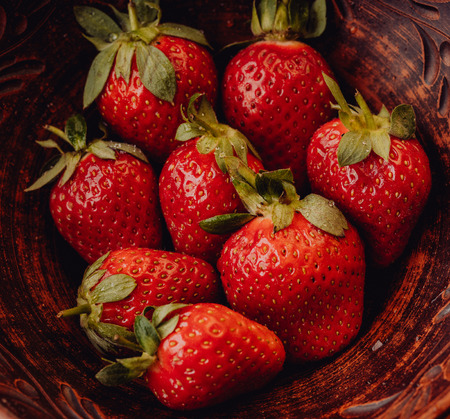 Fresh strawberries in a clay plate. Fresh berries on the table. Red strawberries in a brown bowl. Fruit close-upの写真素材
