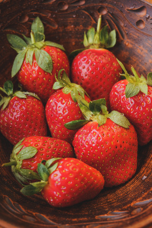 Fresh strawberries in a clay plate. Fresh berries on the table. Red strawberries in a brown bowl. Fruit close-upの写真素材
