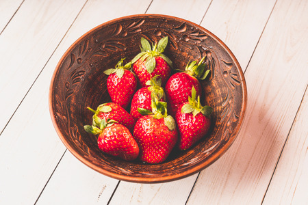 Fresh strawberries in a clay plate. Fresh berries on the table. Red strawberries in a brown bowl. Fruit close-upの写真素材