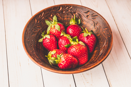 Fresh strawberries in a clay plate. Fresh berries on the table. Red strawberries in a brown bowl. Fruit close-upの写真素材