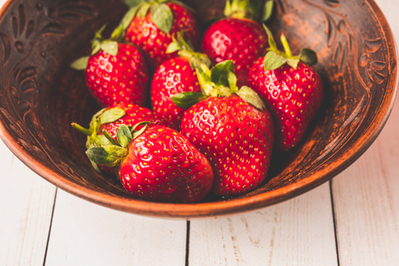 Fresh strawberries in a clay plate. Fresh berries on the table. Red strawberries in a brown bowl. Fruit close-upの写真素材