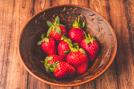 Fresh strawberries in a clay plate. Fresh berries on the table. Red strawberries in a brown bowl. Fruit close-upの写真素材