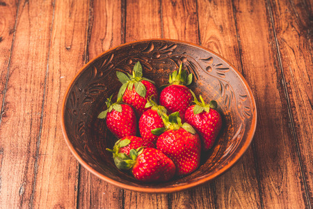 Fresh strawberries in a clay plate. Fresh berries on the table. Red strawberries in a brown bowl. Fruit close-upの写真素材