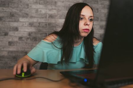 Young woman using laptop computer sitting in front of white brick wall background, people and...
