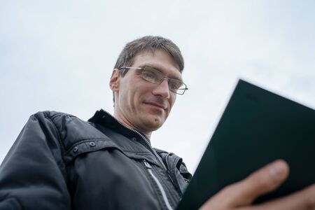 Man reading book in green hilly field
