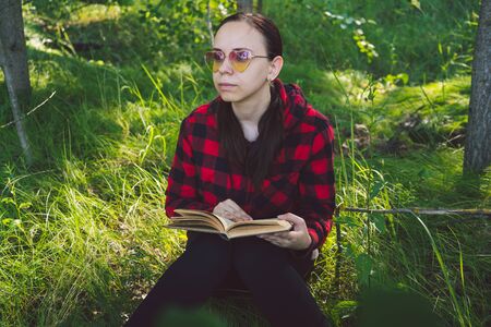 Young handsome woman reading book in open spaceの写真素材