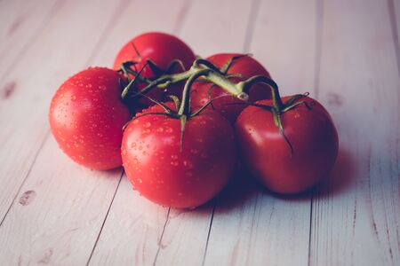 Ripe tomatoes with water drops on tableの写真素材