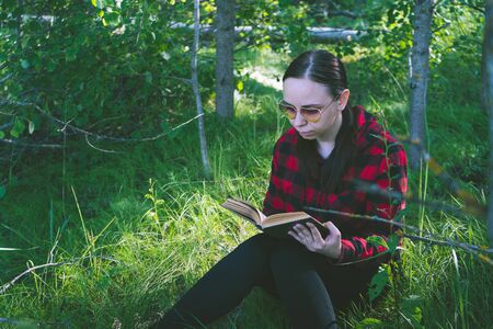 Woman reading a book in a green summer forest.の写真素材