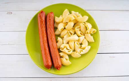 pasta and sausages in a green plate on a wooden table. pasta in closeupの写真素材