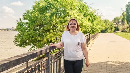 Portrait of a beautiful smiling woman is standing on the waterfront near the water.の写真素材