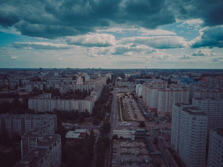 Drone view of new building complex in city center with houses and roads under cloudy skyの写真素材