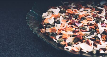 Seasoning a mixture of dried vegetables in a plate on a black background.の写真素材